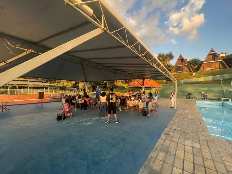 Área coberta com mesas ao lado da piscina